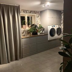 a washer and dryer sitting in a room next to a window with curtains