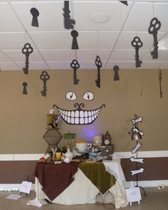 an assortment of keys hang from the ceiling above a table with a smiling face on it