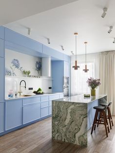 a kitchen with blue cabinets and marble island in the center, along with bar stools