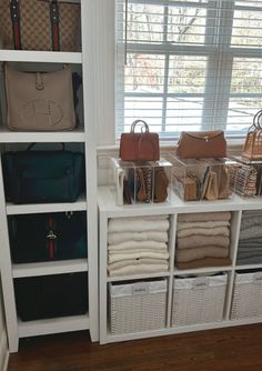 a white shelf filled with purses and handbags on top of shelves next to a window