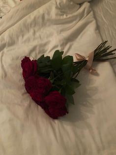 a bouquet of red roses laying on top of a bed