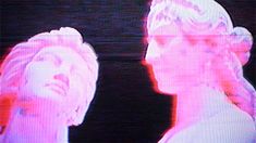 two people standing next to each other in front of a tv screen with pink and red lights