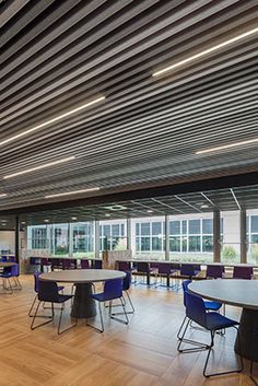 an empty room with tables and chairs in the center, along with large windows on both sides