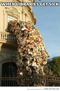 a giant bear made out of books on the side of a building next to a gate