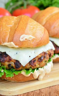 two chicken burgers sitting on top of a wooden cutting board