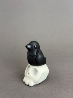 a small black and white bird sitting on top of a skull shaped object in the shape of a human head