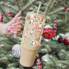 a woman's hand holding a coffee cup in front of a decorated christmas tree