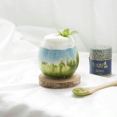 a green and white vase sitting on top of a wooden stand next to a jar