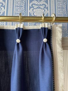 two blue curtains hanging from a gold curtain rod