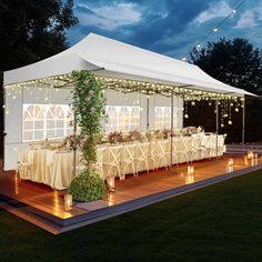 a large white tent set up with tables and chairs for an outdoor event at night