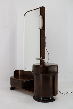 an old fashioned wooden vanity with mirror and plugged in hair dryer on it