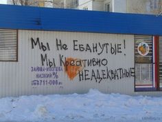 graffiti written on the side of a building in winter time, with windows and shutters open