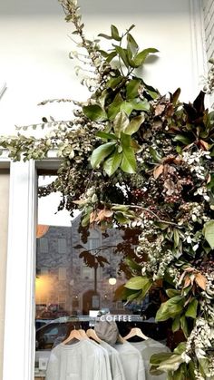 an open window with clothes hanging in front of it and plants growing on the windowsill