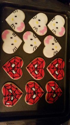 hello kitty decorated cookies in the shape of heart shaped cats and spiderman faces on a cookie sheet