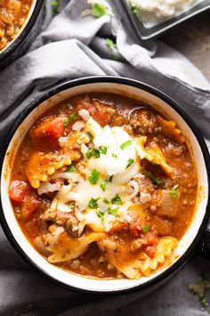 two bowls filled with chili and cheese on top of a table