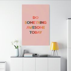 a pink poster with the words do something awesome today on it next to a yellow lamp