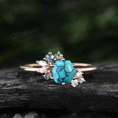 a turquoise and white stone ring sitting on top of a piece of wood