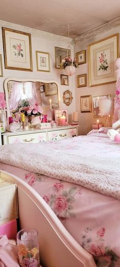 a bedroom decorated in pink and gold with pictures on the wall above the bed, along with candles