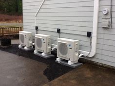 three air conditioners are lined up against the side of a house