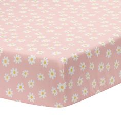 a pink bed sheet with white and yellow daisies on the bottom, in front of a white background