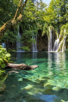 the water is crystal green and there are waterfalls in the background with clear blue skies