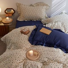 a bed with blue and white sheets, pillows and a candle on it