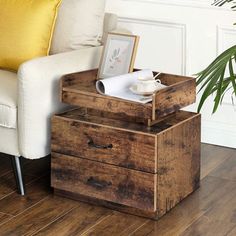 a chair with a yellow pillow on top of it next to a wooden table and two drawers