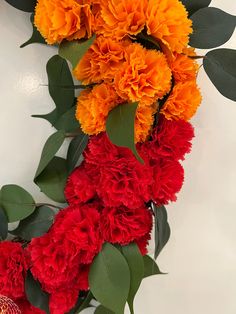 orange and red flowers are arranged on the wall