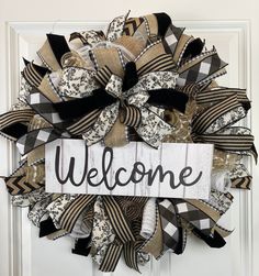 a welcome sign hanging on the front door with ribbons attached to it's side