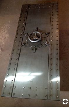 a metal door with rivets and a round knob on the front is shown