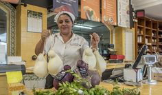 a woman holding up two onions in front of her face and standing behind a counter