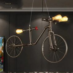 a bicycle hanging from the ceiling in a room with black walls and leather couches