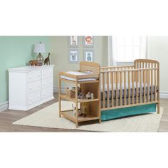 a baby crib in a room with green walls and white furniture, including a dresser