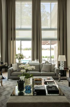 a living room filled with lots of furniture and large windows covered in draping