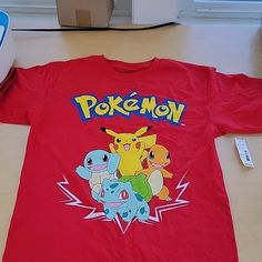 a red shirt with pokemon on it sitting next to a nintendo wii game console controller