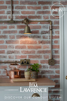 a brick wall with a lamp and potted plant on the counter next to it