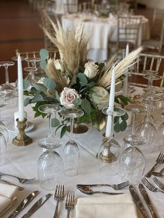 the table is set with wine glasses, silverware and flowers