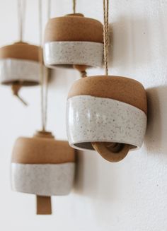 three ceramic pots hanging from hooks on a wall