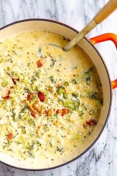 a pot filled with broccoli and cheese on top of a marble countertop