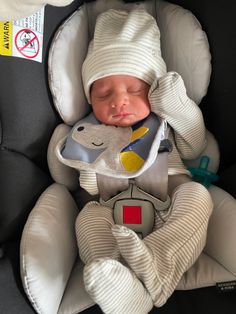 a baby sleeping in a car seat wearing a hat