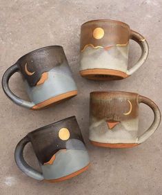 three coffee mugs sitting next to each other on a cement floor with the moon and stars painted on them