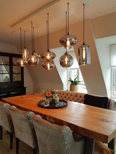 a dining room table with chairs and lights hanging from the ceiling