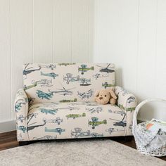 a teddy bear sitting on top of a couch next to a basket and rug in a room