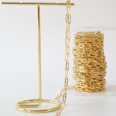 a pair of gold bracelets and a spool of chain on a white background