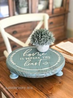 a small potted plant sitting on top of a wooden table next to a white chair