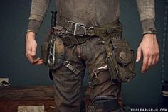 a man with his hands in the pockets of his pants, holding a knife and tool belt