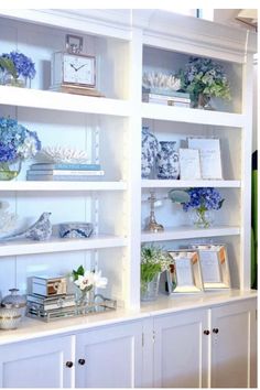 a white bookcase filled with lots of books and vases on top of it