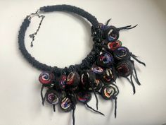 a black necklace with multicolored beads and tassels on a white surface