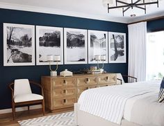 a bedroom with black walls and pictures on the wall above the bed, along with a white chair