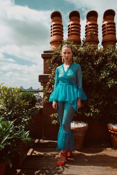 a woman is standing in front of some potted plants and posing for the camera